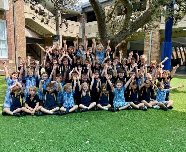 Photo of kinder cohort with their arms up in excitement.
