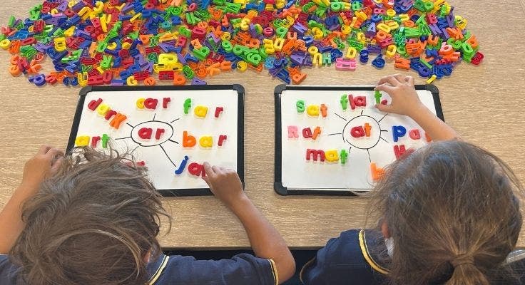 Two students using magnetic letters to create words.