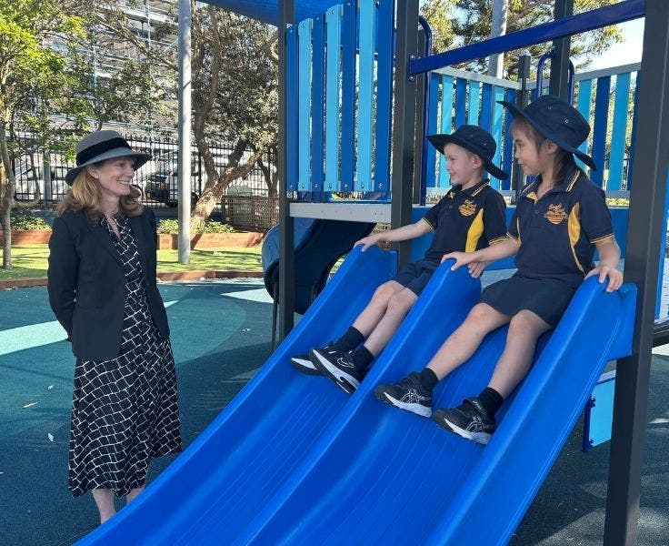 Photo of our school principal with two students playing on the slide.