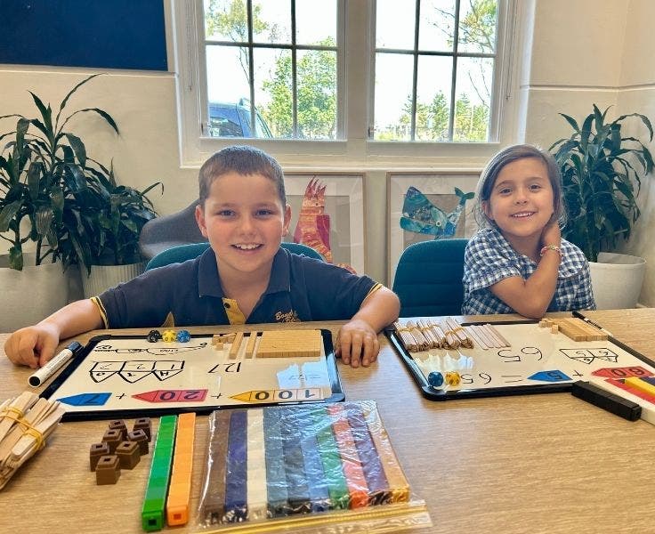 Two students engaged in number activities using hands on concrete materials.
