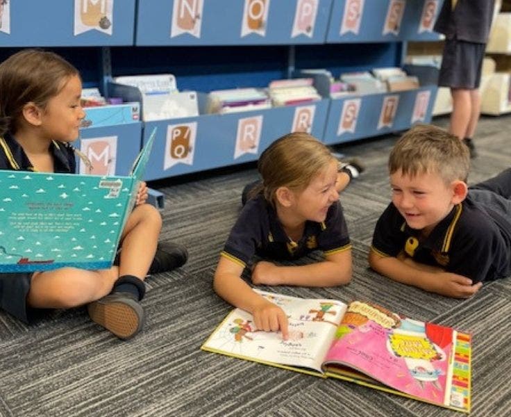 Photo of three students reading in the library.