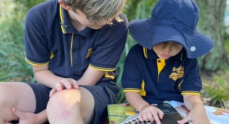 A senior buddy with a kinder student, reading together.