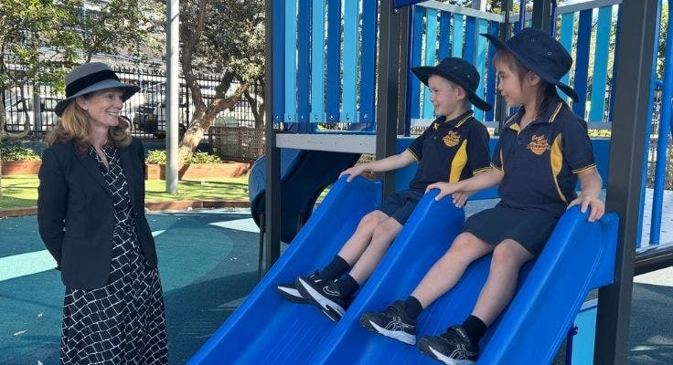 Photo of our school principal with two students playing on the slide.
