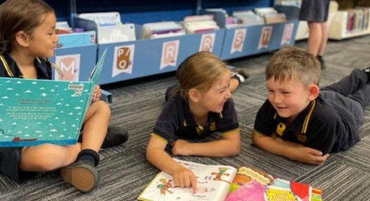 Photo of three students reading in the library.