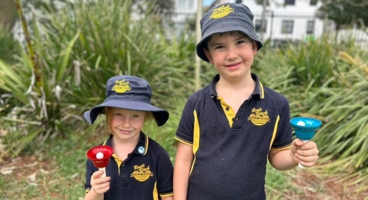 A boy and girl ringing a bell.