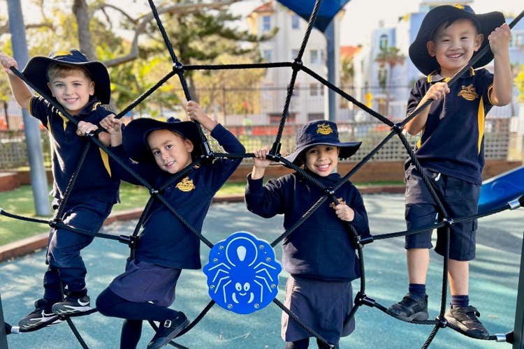 Image of four students climbing on playground equipment.